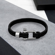 Load image into Gallery viewer, Black braided cord bracelet with silver clasp on a gray surface