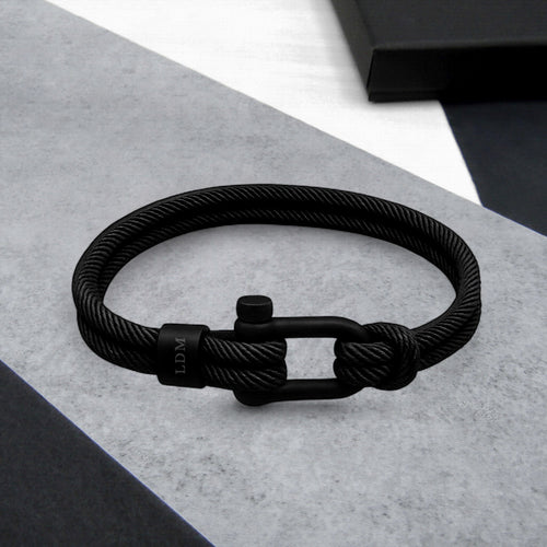 Black braided bracelet with a clasp on a gray surface