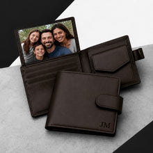 Load image into Gallery viewer, Black leather bifold wallet shown open and closed on a light gray surface with a black-and-white geometric background. The wallet has card slots, a photo ID window holding a family portrait, a flap pocket, and a strap closure.