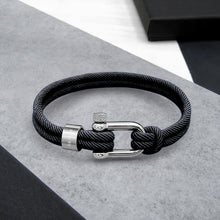Load image into Gallery viewer, Black braided cord bracelet with silver clasp on a gray surface