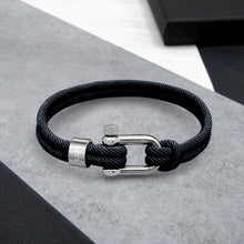 Load image into Gallery viewer, Black braided cord bracelet with silver clasp on a gray surface